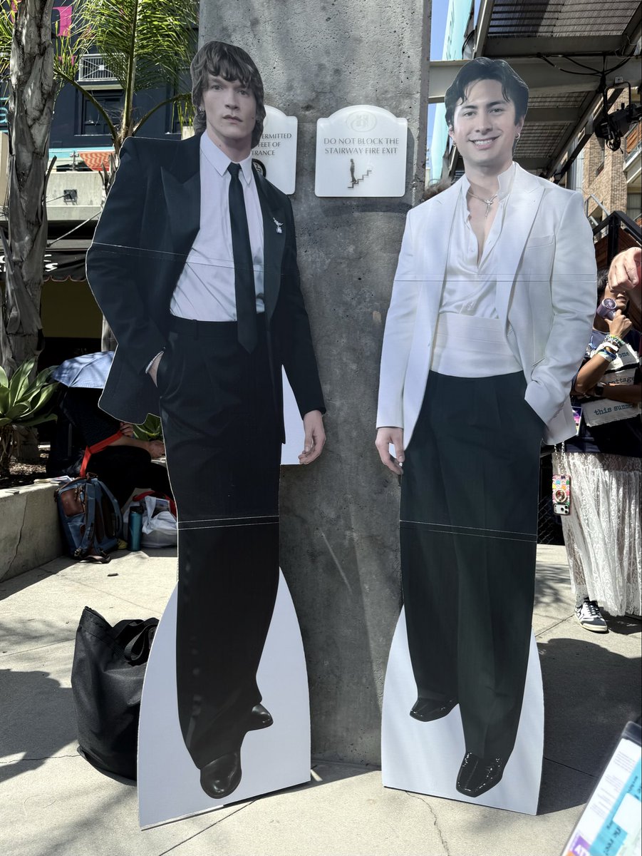 hellowithloveLA's tweet photo. Connor and Hudson cutouts in front of the Yaga building wrap lol! Yaga pink in the corner. And all the little gifts from fellow Heated Rivalry fans. @tara_taralynn thanks for bringing everyone together. Hope to do it again next year! #HRMeetupSDCC https://t.co/n2TuF3of6L