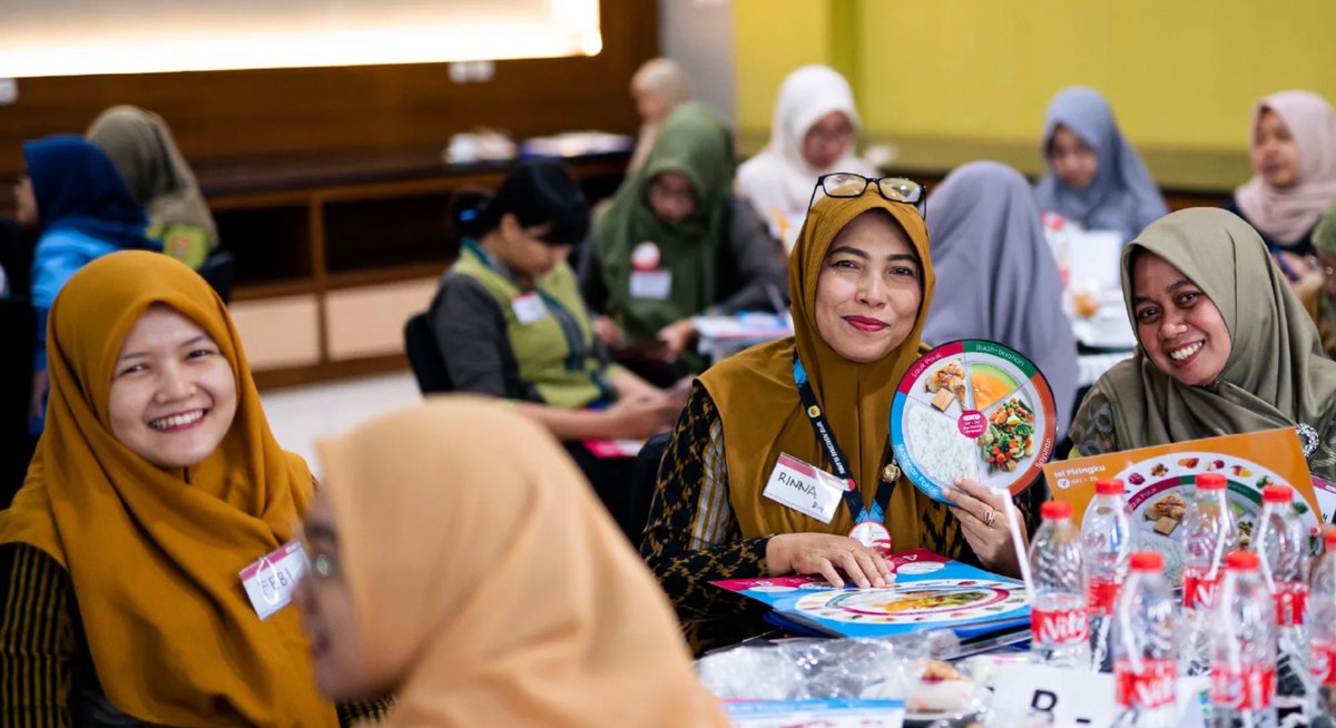 Group of women wearing hijabs smiling and engaging in a workshop with tools from the Care Companion Program at a workshop in Indonesia.