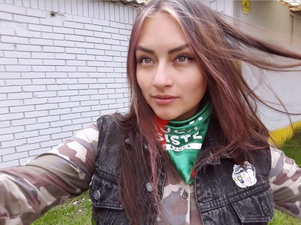 JaviPekerman's tweet photo. Lenguaje no verbal:
Pañoleta que representa a una organización indígena denunciada por la misma comunidad indígena de entregar menores de 14 años a las FARC para el reclutamiento forzado. Prenda superior camuflada representando un grupo armado ilegal.  @smilelalis reclutadora. https://t.co/SeA3dl1R7m