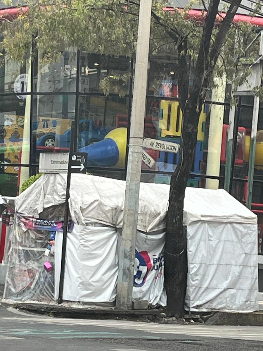 MixcoacAvanza's tweet photo. Fue fijado al pavimento con mezcla y postes. Además ocupa la banqueta con refrigerador, mercancía y enseres. Resulta contradictorio que la invasión esté cubierta con una lona de “Orgullo BJ”. @SPAOVP_CDMX @locatel_mx @BJAlcaldia @AccionesBJ @LuisMendozaBJ #EspacioPublico #InsurgentesMixcoac