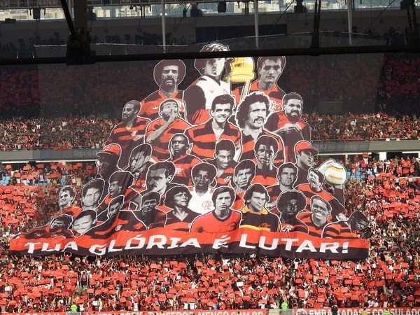 ubzoficial's tweet photo. A final da Copa do Brasil de 2023 não terminou do jeito que queríamos, mas a festa no primeiro jogo está entre as maiores do Maracanã.

A URUBUZADA lançou uma vaquinha para a confecção de bandeirolas para a decisão. A Nação Rubro-Negra chegou junto e protagonizamos uma linda festa no recebimento das equipes.

Com bandeiras de mastro, bandeirolas, fumaça, salsichões, faixas verticais, mosaico de papel e o mosaico 3D dos ídolos, fizemos festas em todos os setores do Maracanã.

Uma recepção a altura da torcida do FLAMENGO.

#URUBUZADA
#DefensoresdoManto
#UBZ20anos