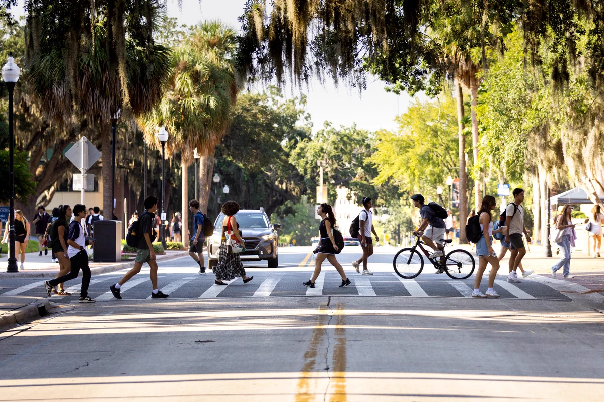 Students walking across the street with a mossy tree hanging over them