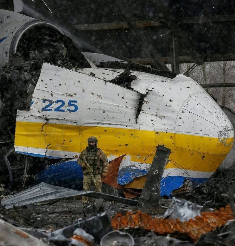 GZsgallos2007's tweet photo. An operative of the "Bulat" special unit of the State Guard of Ukraine in front of the wreckage of the An-225 Mriya. The photo was taken in the spring of 2022, after Russian Federation forces withdrew from the region. https://t.co/d5m6SUxqo1