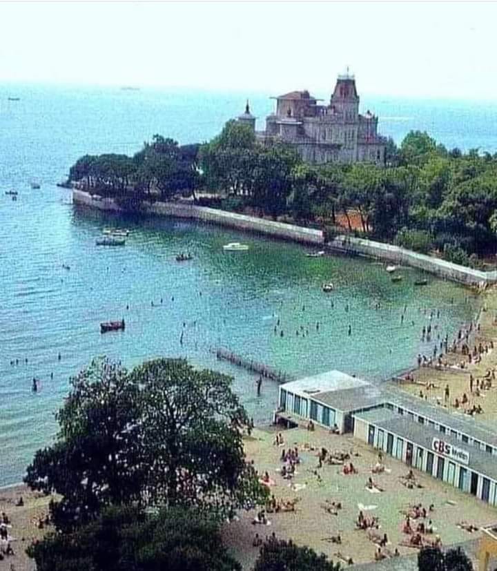 CNybak's tweet photo. This 1970s photo shows Caddebostan Beach in Kadıköy, Istanbul, before the coastal highway was built.

 In the background stands the iconic Ragıp Paşa Köşkü (Ragıp Pasha Mansion), overlooking the Marmara Sea. https://t.co/0lWMdCRb54