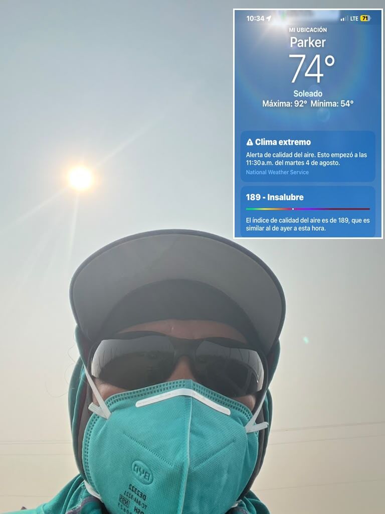 UFWupdates's tweet photo. "Joel" shares, "We're staking young apple trees, tying them to support them against the wind in Parker WA. We're wearing  masks as protection from the polluted air, but it's still bad. I leave with a headache and very irritated eyes. The AQI is 189. I earn min. wage."  #WeFeedYou https://t.co/TaqiD52IZe