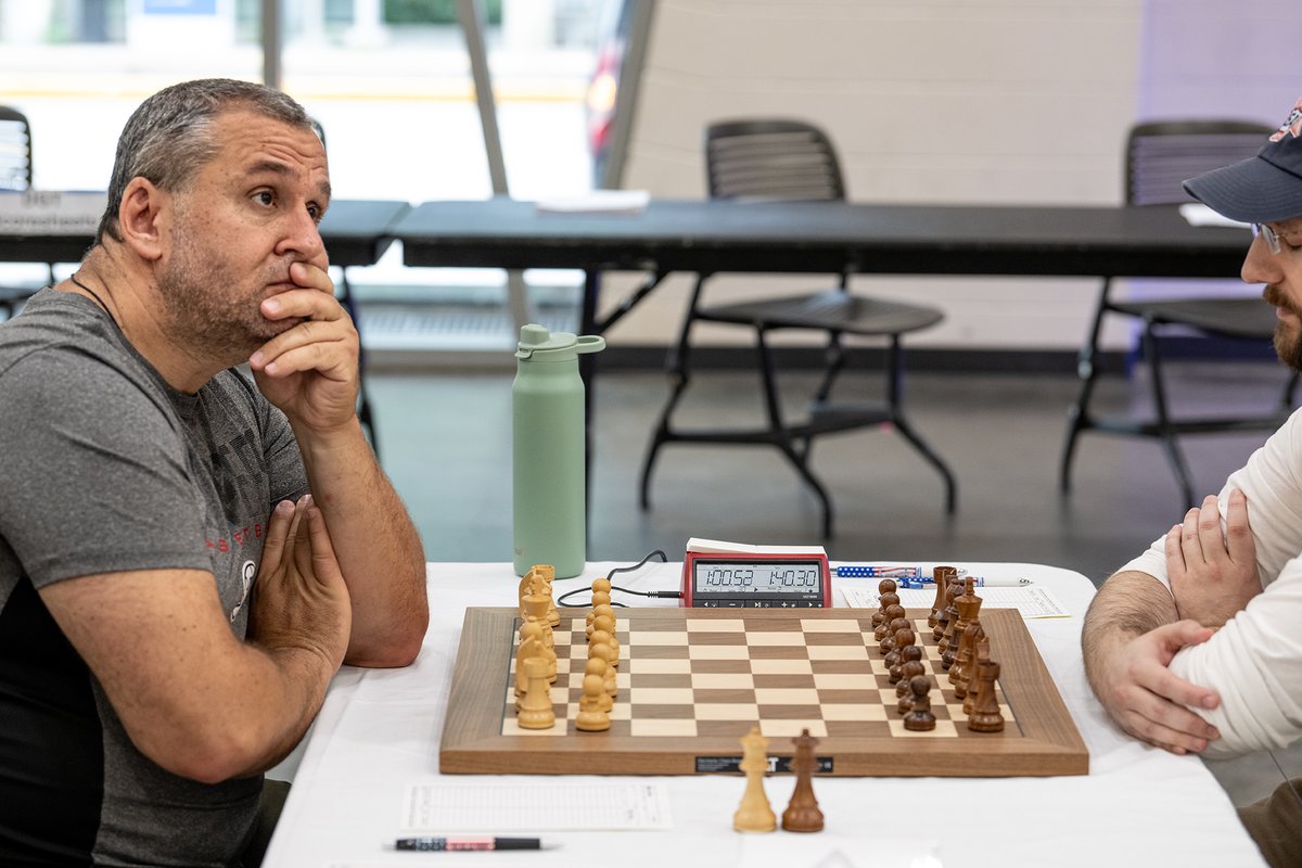 davidllada's tweet photo. Here is something I had never seen before: the player with White, Dmitry Kishinevsky, arrived 40 minutes late. He then sat down and spent the next seven minutes contemplating the board with a perplexed expression, as if he had never seen a wooden horsey before.

He asked his opponent something, adjusted a few pieces, and then stared at the ceiling for several more minutes before finally playing 1.Nf3. He came within a few minutes of forfeiting the game.

Psychological warfare? Ivanchuk syndrome?