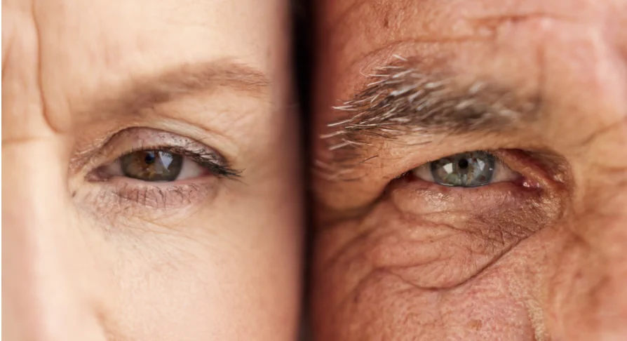 Close-up image split down the middle showing two human eyes. The left side features a younger person's eye with smooth skin, while the right side shows an older person's eye with wrinkles and gray eyebrow hair, highlighting visible changes associated with aging.