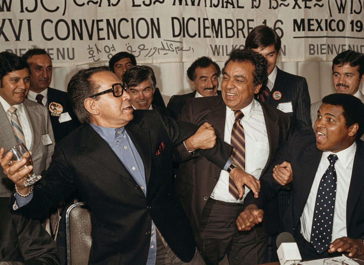 Cuauhtemoc_1521's tweet photo. Sabías que Cantinflas “retó” a Muhammad Ali en la Ciudad de México?

Esta extraordinaria fotografía fue captada en diciembre de 1980, durante una Convención del Consejo Mundial de Boxeo (CMB) celebrada en la Ciudad de México. En ella aparecen tres figuras legendarias: Mario Moreno “Cantinflas”, Muhammad Ali y José Sulaimán, presidente del organismo que transformó el boxeo mundial. En medio de un ambiente de camaradería, Cantinflas protagonizó uno de los momentos más memorables del evento al desafiar, en tono completamente humorístico, al campeón estadounidense. Incluso le reclamó que “no quisiera pelear con él” y, siguiendo su característico estilo cómico, tomó un vaso e hizo el ademán de lanzárselo, provocando las risas de los asistentes. José Sulaimán intervino como improvisado “réferi” y mediador de aquel singular encuentro.

Aunque Muhammad Ali jamás disputó una pelea profesional en México, visitó el país en diversas ocasiones gracias a la estrecha amistad que mantenía con José y Elías Sulaimán, quienes lo recibían con frecuencia en eventos relacionados con el boxeo.
