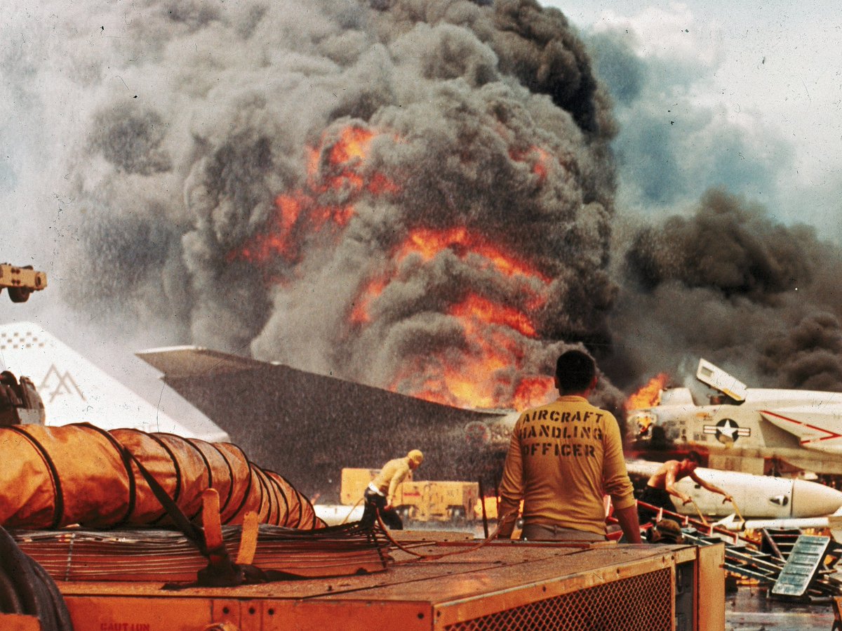 VoicesfromNam's tweet photo. July 29, 1967. In the Gulf of Tonkin off the coast of North Vietnam, the aircraft carrier USS Forrestal was launching strikes when a freak accident set off one of the worst disasters in US Navy history. By the time the fires were out, 134 men were dead. Not one of them was killed by the enemy.

Start with the bombs, because they matter. The day before, an ammunition ship had handed Forrestal sixteen old 1,000 pound bombs, Korean War leftovers, some stamped 1953. They had been sitting in the open in the Philippines for years, and they came aboard rusty, moldy, and actually leaking, a sign the explosive filler inside had gone unstable with age. The ship's ordnance men had never seen bombs like them and begged to dump them over the side. The captain tried to trade them back and was told there was nothing else. He needed 1,000 pound bombs for the next day's missions, so he reluctantly kept them, and had them set apart on the deck, away from the magazines.

The morning of the 29th, the aft flight deck was jammed wing to wing with 27 fueled and armed aircraft waiting to launch the second strike of the day. At about 10:51, an electrical surge caused a Zuni rocket under one of the F-4 Phantoms to fire by accident. It shot roughly a hundred feet across the packed deck and tore open the external fuel tank of an A-4 Skyhawk. Hundreds of gallons of jet fuel gushed out onto the deck and ignited in an instant, whipped into an inferno by a 32 knot wind. One of the pilots sitting in that pack of Skyhawks was a young aviator named John McCain. He scrambled out of his cockpit, climbed down the refueling probe on the nose, and jumped through the flames to escape.

Then came the part that turned a fire into a catastrophe. In the years before this, the Navy had stopped training all its sailors to fight fires and instead relied on small teams of specialists. Forrestal's deck team was led by a chief named Gerald Farrier. They had been trained on film showing that a 1,000 pound bomb could sit in a fuel fire for a full ten minutes before anyone had to worry. But those test films used modern, heat resistant bombs. The rusty old bombs now cooking in the flames on Farrier's deck were nothing like them. Chief Farrier saw a bomb lying in the burning fuel, and rather than wait, he ran to it with a single hand held extinguisher and tried to hold the fire back with his own body to buy the trapped pilots time to get out. He had no protective gear on. The bomb's casing split, he shouted for his men to run, and it detonated about a minute and a half after the fire began. The blast killed Chief Farrier and nearly his entire firefighting team instantly. In one explosion, the ship lost almost every man trained to save it. John McCain, who had turned back to help another burning pilot, was thrown ten feet and cut with shrapnel.

After that, it was untrained teenagers against hell. More bombs cooked off, ten of them in all, some blowing craters straight through the armored flight deck. Around 40,000 gallons of burning jet fuel poured down through the holes into the berthing compartments below, where dozens of men from the night crew were asleep. Fifty of them died down there. The fire raged across the deck and burned deep in the ship's guts for hours. Sailors did unbelievable things. An explosive ordnance officer named Robert Cates defused smoking live bombs by hand and had himself lowered on a rope into a burning, smoke filled compartment to hook a line onto a bomb so it could be dragged out and thrown overboard. A destroyer, the Rupertus, pulled to within twenty feet of the blazing carrier and poured water on the flames for an hour and a half, an act the admiral called magnificent seamanship.

They did not get the flight deck fire under control until almost noon, and the fires deep in the lower decks burned until after midnight, roughly fourteen hours in all. When it was over, 134 sailors and airmen were dead, 161 were injured, and 21 aircraft were destroyed. It took nearly five months in the shipyard to rebuild the ship, replacing 175 feet of flight deck and some 200 compartments.

John McCain survived, and rather than go home he volunteered for another carrier. Three months later he was shot down over Hanoi and spent five and a half years as a prisoner of war. And the Navy learned. It went back to training every single sailor to fight fire, built automatic deck washdown systems into its carriers, and named its firefighting school in Norfolk after Chief Farrier, the man who ran at a live bomb with a fire extinguisher so his pilots could live. New sailors still watch the real footage of that day. The Forrestal was not lost to any enemy. It was lost to a spark, an old bomb, and a hard lesson written in the lives of 134 men.