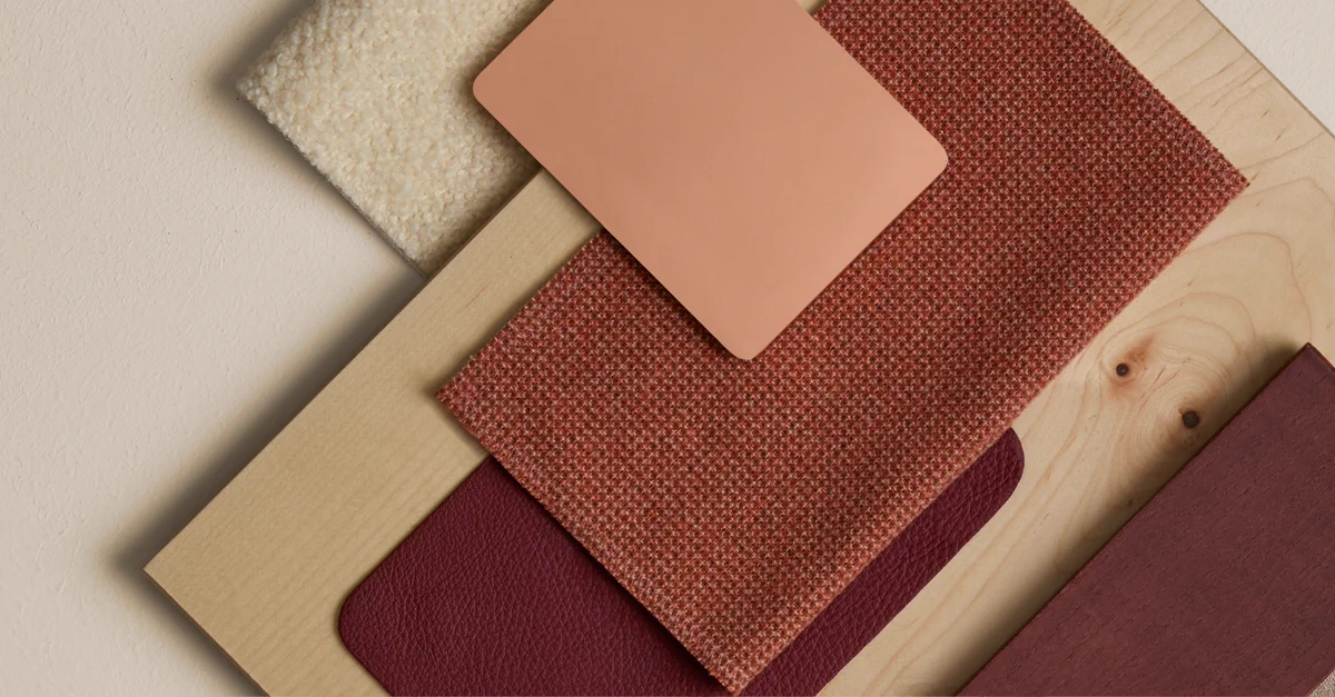 Flat lay of various textured fabric and wood samples in warm earthy tones arranged on a light surface.