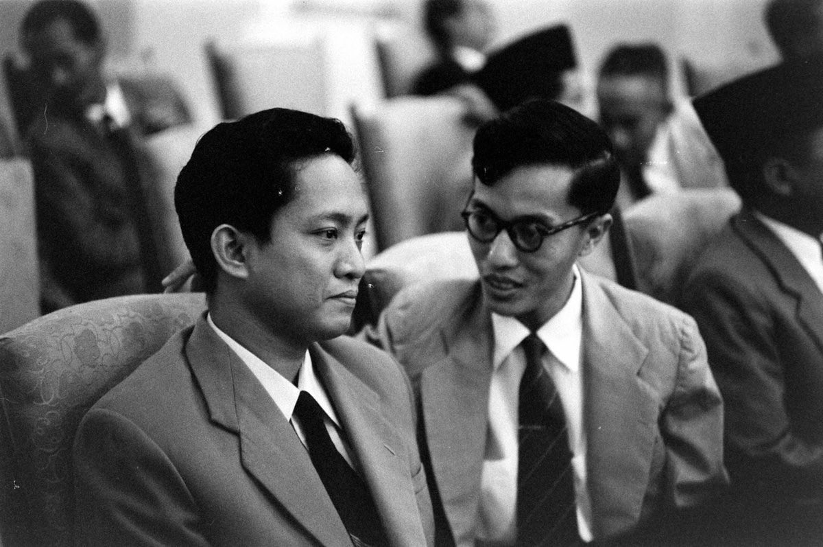 tatap's tweet photo. Anak muda itu usianya baru saja 28 tahun, namun ia didapuk menjadi Sekjen sebuah partai di tahun 1951. Namanya Dipa Nusantara Aidit.

Inilah kisahnya.

Ia dilahirkan pada hari yang sekarang dilupakan orang, 30 Juli 1923, di sebuah pulau kecil bernama Belitung, dengan nama yang masih sederhana: Achmad Aidit. Keluarganya tergolong terdidik menurut ukuran zaman itu, cukup untuk memberikan anaknya akses ke huruf-huruf dan ide-ide yang kelak akan membawanya jauh dari tanah kelahirannya.

Sejak muda ia memasuki dunia yang gelap dan penuh bisikan: organisasi kiri, gerakan kemerdekaan, pertemuan yang diadakan di ruang-ruang sempit. Setelah kemerdekaan dicapai, ia bergabung dengan Partai Komunis Indonesia yang saat itu masih kecil, terpecah-belah, hampir seperti sebuah sekte yang kehilangan jalannya. Ia menambahkan pada namanya dua kata yang terdengar seperti ramalan: Dipa Nusantara. 

Orang-orang kemudian mengenalnya hanya sebagai DN Aidit, seolah-olah nama yang lebih panjang itu terlalu berat untuk diucapkan.

Pada awal tahun 1950-an, bersama beberapa pemuda lain yang sama ambisiusnya: Njoto, Lukman, Sudisman, ia mengambil alih kepemimpinan partai. Usianya baru dua puluh delapan tahun. Di bawah tangannya yang tenang dan terampil, partai yang semula seperti pohon kerdil berubah menjadi hutan. 

Dalam waktu singkat PKI menjadi partai komunis non-pemerintah terbesar di dunia, dengan jutaan anggota yang tersebar di sawah-sawah Jawa dan di gang-gang kota. Ia tidak berteriak. Ia mengatur.
Aidit adalah seorang pragmatis di tengah ideologi yang mengklaim kesucian. Ia menerima konsep Nasakom yang digagas Sukarno, menempatkan komunisme berdampingan dengan nasionalisme dan agama seolah-olah ketiganya bisa hidup dalam satu rumah tanpa saling membunuh. 

Ia menghindari konfrontasi langsung dengan tentara. Ia lebih suka merayap melalui serikat-serikat buruh, organisasi massa, dan dukungan terhadap kebijakan-kebijakan Presiden yang semakin radikal. Di mata banyak orang, partainya tampak patriotik, nasionalis, bahkan “progresif revolusioner”. 

Di mata yang lain, terutama para perwira dan tokoh-tokoh agama, ia adalah bayangan yang semakin panjang di dinding.

Kemudian datang malam yang mengubah segalanya. Gerakan yang terjadi pada pergantian September-Oktober 1965 digambarkan oleh kekuasaan baru sebagai kudeta yang dirancang di ruang-ruang gelap PKI, dengan Aidit sebagai dalangnya. Sejarah resmi menuliskannya sebagai pengkhianat. 

Tubuhnya ditemukan beberapa minggu kemudian di Boyolali, dieksekusi tanpa pengadilan, seperti begitu banyak tubuh lain yang tidak lagi memiliki nama.

Bertahun-tahun kemudian, dari sebuah universitas di seberang lautan, seorang asing bernama Benedict Anderson menuliskan sesuatu yang berbeda. Bersama Ruth McVey ia menyusun sebuah analisis yang kemudian dikenal sebagai Cornell Paper. 

Di dalamnya dikatakan bahwa gerakan itu lebih merupakan konflik internal di dalam tubuh tentara sendiri; bahwa PKI dan Aidit bukan dalang utama, melainkan korban atau paling banter peserta yang datang terlambat; bahwa yang memanfaatkan kekacauan itu adalah pihak yang kemudian naik ke takhta. 

Paper itu, yang awalnya ditulis untuk kalangan terbatas, bocor. Anderson dilarang menginjakkan kaki di Indonesia selama hampir tiga dasawarsa.
Ia tidak membela Aidit. Ia hanya menolak agar sejarah disederhanakan menjadi dongeng tentang satu penjahat tunggal. Ia memaksa orang untuk melihat bahwa di balik satu nama yang dihukum, ada mesin kekuasaan yang jauh lebih rumit, dan bahwa korban-korban yang tidak terhitung jumlahnya telah dikubur di bawah narasi yang terlalu rapi.

Setelah rezim berganti, sebagian orang mulai membaca kembali kisah itu dengan mata yang berbeda. Aidit muncul kembali bukan lagi sebagai monster, melainkan sebagai seorang politisi yang cerdas, terlalu percaya pada perlindungan seorang presiden, dan akhirnya menjadi salah satu dari ratusan ribu orang yang hilang tanpa jejak yang layak. 

Sejarah, seperti biasa, tetap diam.