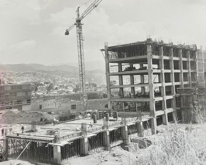 enlaucab's tweet photo. #TBTucab | En los años 60, para dar vida al corazón del nuevo campus, la UCAB confió en la visión del prestigioso arquitecto argentino Julio Volante. El resultado fue una de las obras más emblemáticas de la universidad: el Edificio de Aulas, conocido afectuosamente como «La Colmena» por la trama hexagonal que viste su fachada.

Esta imponente estructura de cinco plantas es un referente de la arquitectura brutalista, erigida con un virtuoso dominio del concreto armado y la obra limpia. Concebida con una ingeniería de vanguardia y estándares de cálculo estructural de máxima exigencia, la edificación fusiona estética y funcionalidad: sus característicos muros calados actúan como un sabio aislante térmico, mientras que su esqueleto de alta densidad le otorga una firmeza impertérrita, capaz de absorber con entereza las convulsiones del tiempo y de la naturaleza.