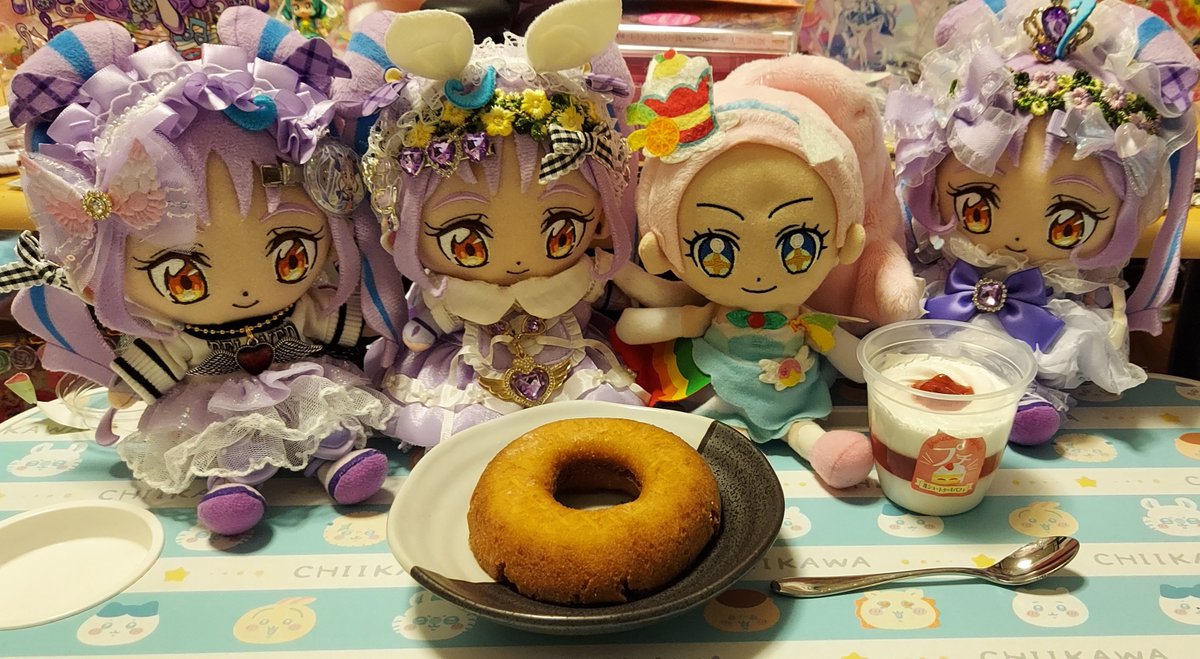 QQHBDXQarQaUX8q's tweet photo. プリキュア！ぬい活劇場💜👏

キュアパルフェのお誕生日🎂
スイーツでキュンキュン💜の巻✨️

パルフェ「あれ～？確かここよね？
招待状の案内だと…でも真っ暗で何も見えない…。
誰かいませんか～⁉️」

パン🎉パン🎉パパン🎉🎉

パルフェ「(*゜д゜*)⁉️何⁉️」

キュン様シスターズ「キュアパルフェ‼️お誕生日おめでとう～😆💜💜💜
ようこそ🎵私達のお家へ✨️」

パルフェ「オ～メルシー😆✨
キュンちゃんシスターズ‼️
ビックリしたわ🎵
招待してくれてありがとう😆💕」

キュン姉「初めまして！キュアパルフェさん😌
こちらこそ！来ていただき光栄です✨️」

キュン次女「今日は、パルフェお姉ちゃんのお誕生日をお祝いするために、私達がスイーツを用意したよ～😆」

キュン三女「スイーツのお話しも聞きたいです😌🎵
食べながらお話ししましょう😆」

パルフェ「トレビア～ン✨
オ～これは…ドーナツ🍩にショートケーキ🍰パフェね🎵
キュンちゃん達のキラキラルがいっぱい詰まっていて幸せな気持ちになるわ～😌
ドーナツはペコリンが作って食べさ��てくれた事を思い出すし、ショートケーキパフェを見ているとキュアホイップのことも思い出すわ～😆」

キュン姉「喜んでくれて良かった���す‼️私の淹れた紅茶もありますので、どうぞ😌💜」

パルフェ「メルシー🎵じゃあ、早速いただくわ🎵」

キュン様シスターズ「召し上がれ～😆🎵💜」

パルフェ「モグモグ…美味しいわ～😆
🎵
やっぱり！スイーツは皆を笑顔にして楽しませてくれる素晴らしい物だわ‼️」

キュン三女「パルフェお姉ちゃんは一流のパティシエなんですよね？？
特に！好きなスイーツはなんですか⁉️」

パルフェ「ええ❗そうよ‼️
自分のお店も持っているわ🎵
そうね…やっぱりパフェかしら😉
色んな果物をデコレーションしたり、彩ったりして、見ていても飽きない‼️最高のスイーツだと思うわ🎵
パルフェ😉
キュンちゃん達は何のスイーツが好きなの⁉️」

キュン姉「わたしは…チョコレートケーキが好きかな✨
甘くてほろ苦い感じ���好きなんです😌」

キュン次女「わたしは！プリン！😆
プリン・アラモードが一番大好物😋💜」

キュン三女「わたしは、アイスとマカロンかな🎵
アイスは色んな味を楽しめるし、マカロンは可愛くて大好き😍」

パルフェ「オ～トレビアン😊
あれ⁉️プリアラの仲間達が、いつの間にか話題になってる気がするわ🎵
今日用意してくれたスイーツとキュンちゃん達の好きなスイーツの思いがプリアラの仲間達にも伝われば最高にパルフェ😉な気持ちになるわ🎵」

キュン姉「いつかキラパティにも行ってみたいよね⁉️」

キュン次女「そうだね！お姉ちゃん😆絶対に行こうよ🎵」

キュン三女「私も！私も！！
あと…パルフェお姉ちゃんのお店にも行きたいな～😆💜」

パルフェ「それなら今日のお礼に私のお店にご招待してあげるわ🎵」

キュン三女「えっ⁉️良いんですか⁉️」

パルフェ「ええ！構わないわよ🎵」

キュン姉「なら、パルフェさんのお言葉に甘えて行っちゃおうか！😆💜」

パルフェ「ウィー😉
それなら、スイーツのフルコースなんてどうかしら⁉��🤭
私！腕を振るっちゃうわ🎵✨️」

キュン次女「スイーツのフルコース…🤤考えただけでお腹空いてきちゃった😋🎵」

キュン姉「コラコラ！次女！ヨダレが垂れてるよ(笑)」

キュン三女「次女お姉ちゃんの食いしん坊～😆💜」

キュン次女「だって‼️スイーツのフルコースなんて聞いたら…こころキュンキュン止まらないもん😂💜」

パルフェ「(笑)喜んでくれて嬉しいわ😉🎵
もちろん！キラパティのメンバーしかりプリアラのメンバーも来てお・も・て・な・しさせて貰うわ😆‼️🎵
その時は、キュンちゃんシスターズも一緒にスイーツを作りましょ🎵」

キュン様シスターズ「やった～😆🎶
こころキュンキュンしてます😆💜💜💜」

パルフェ「世界中にキラキラルが、これからも溢れますように😌✨️
さぁ！みんなで🎵」

みんな「キラキラキラル✨️キラキラル✴️🌈💜」