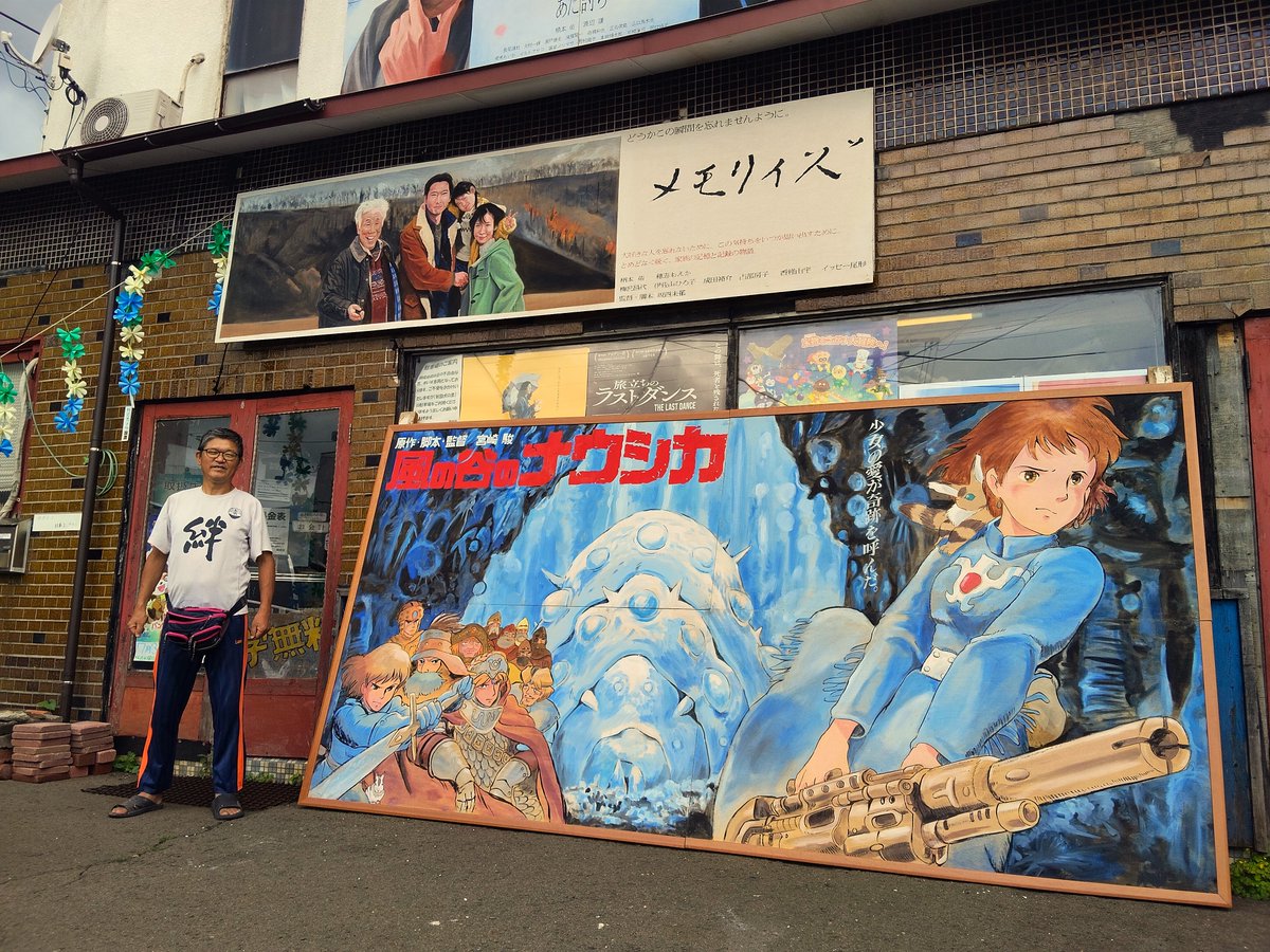 OdateOnariza's tweet photo. ご報告いたします。5年前の春に『アニメージュとジブリ展』での展示のために当館より旅立った『風の谷のナウシカ』絵看板が、国内13ヶ所、そして台湾と韓国での巡回展を経て、昨日ついに当館へと帰って来ました。5年前に見送った際と同じTシャツを着用した、看板絵師との記念の一枚をご覧ください。 https://t.co/x565R2UWRF