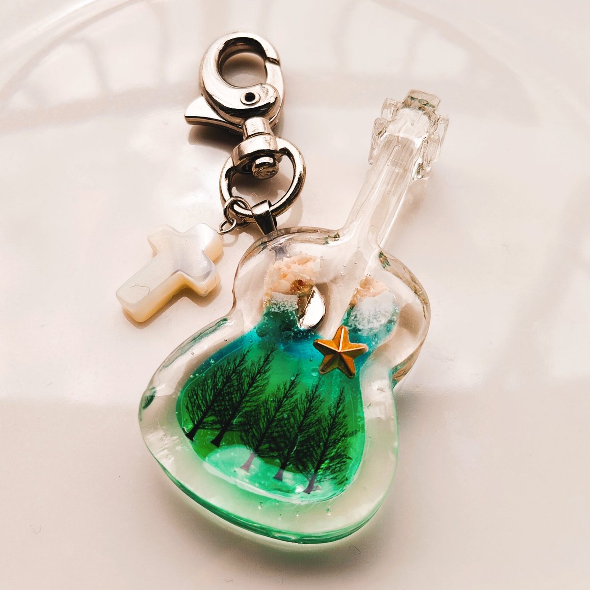 zi95278's tweet photo. レレアク♪
(ウクレレアクセサリー)
￥3200-

ウクレレモチーフの大きさ
縦5.7cm･横2.8cm･厚さ9mm

浜辺の波打ち際のアクアマリンからグリーンにグラデーションを作り、そこに森を表現し、シェルのクロスのチャームを付けました🌳

ご購入希望の方はDMお待ちしております！ https://t.co/KdVyVbpVrB