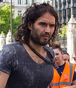 MAGAts_Exposed's tweet photo. "if you care about democracy, if you care about freedom, I don't know how you could do anything other than vote for Donald Trump"
Behold the miraculous transfiguration of alleged sexual predator MAGAt Russell Brand, who has seamlessly traded his skin-tight leather trousers for a camera-ready baptismal gown. It is truly inspiring to watch an aging influencer lock eyes with the Almighty and suddenly clutch a Holy Bible like the ultimate shield against a Southwark Crown Court docket. There is nothing quite like the threat of multiple criminal counts of rape, sexual assault, and indecent assault from six different women to make a man sprint toward a pristine new persona of divine redemption.
The charges agaisnt Brand include:
1999 (Rape): An alleged rape occurring in a hotel room in Bournemouth during a Labour Party conference event.
2001 (Indecent Assault): Brand is accused of grabbing a woman's forearm and attempting to force her into a male restroom at a television studio in Westminster.
2004 (Oral Rape & Sexual Assault): Two separate charges stemming from an incident at a bar during a birthday party in Westminster, involving oral rape and the non-consensual touching of a woman's breasts.
2004–2005 (Sexual Assault): Brand is accused of trapping a woman against a wall, groping her, and forcefully kissing her at a radio station.
2009 (Rape & Sexual Assault): Two additional charges authorized by the Metropolitan Police involving two separate women.
With his criminal trial scheduled for October 2026, Brand has masterfully pivoted from preaching anti-capitalist anarchy to masquerading as a persecuted conservative martyr. The sheer audacity required to rebrand a harrowing history of sexual misconduct allegations into a cozy narrative of spiritual warfare is breathtaking. Apparently, in the gospel according to Russell, the waters of baptism do double duty as a convenient legal eraser to wash away a joint journalistic exposé.
Naturally, this divine reinvention wouldn't be complete without a pilgrimage to the Trump family inner circle. Auditioning for the role of Donald Trump’s chief cheerleader at the Republican National Convention and wearing a "Make Jesus First Again" hat is the perfect final act for a man who used to tell the youth that voting was a scam. It turns out that when the world remembers your alleged victims, the quickest way to find sanctuary is to wrap yourself in the American flag, hold a Bible, and pretend your day in court is just a conspiracy against your newfound piety.
