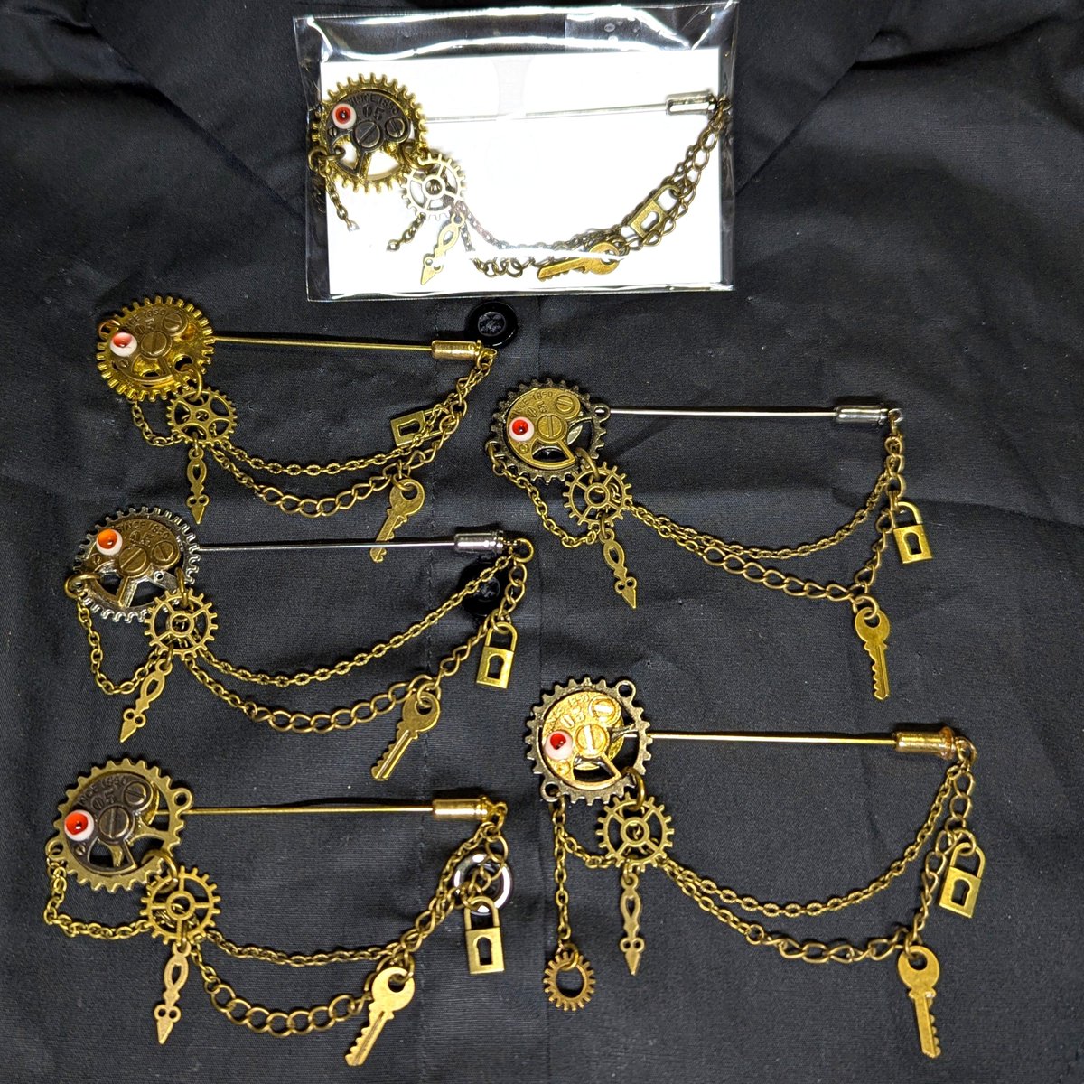 MarronTree's tweet photo. 今日のお仕事はこんな感じでラペルピンの仕上げしてました

前回やりかけてたドラゴンのラペルピンは血色の雫だけのシンプル装飾
満月を背に血涙を零す龍

あとは最小の目玉がアクセントの
時の鍵の歯車のラペルピンと

蝙蝠に吸われて色を無くした薔薇のラペルピン

それぞれ物語を含んだモノばかり♪ https://t.co/XUv5qJra3C