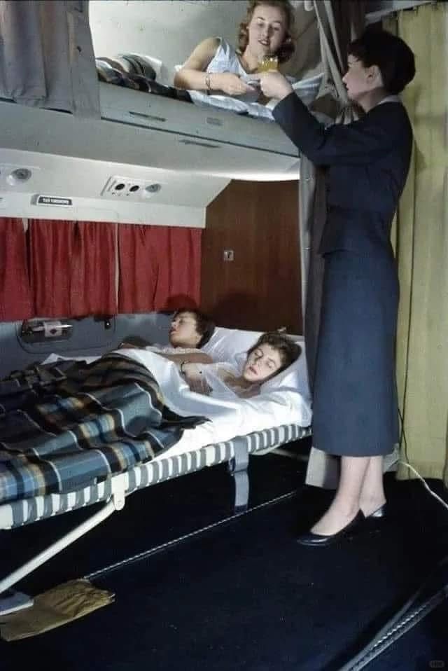 alvinfoo's tweet photo. This is a photo taken in 1950 on KLM. At the time, Martin M-130s, Lockheed Constellations, and Douglas DC-6s operated by airlines such as KLM and the now-defunct Trans World Airlines (TWA) had beds in both the upper and lower berths.

These beds featured mattresses, Pullman-style curtains for privacy, windows, reading lights, and even breakfast-in-bed service.

At the time, a round-trip economy airfare from New York to London on a Boeing 377 Stratocruiser cost about $580 (about $12,000 today). 

The baggage racks as we know them today were phased out during the late 1960s and early 1970s.