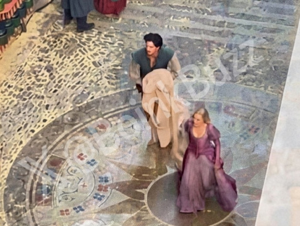 BoinkBuzz's tweet photo. 🚨 𝗡𝗘𝗪! - Set Images from Disney's Live Action Movie "TANGLED"

• Fresh look at Kathryn Kahn's Mother Gothel in full costume

• Filming of the iconic braiding scene. The image captures Teagan Croft as Rapunzel with her long golden hair in a village square decorated with Corona’s sun crest, with Milo Manheim’s Flynn Rider also spotted in the sequence.

• New Scene of Rapunzel and Flynn Rider (Eugene) riding the horse named Maximus

• The King and Queen of Corona riding on horseback across a medieval bridge. The photos offer a first partial look at Queen Arianna, a role rumored to be played by Caitríona Balfe. The actor behind King Frederic has not been revealed, though rumors point to Diego Luna.