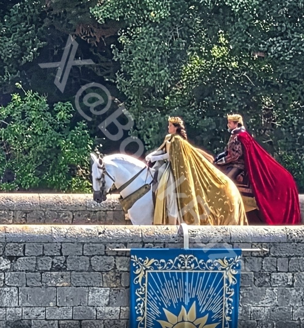 BoinkBuzz's tweet photo. 🚨 𝗡𝗘𝗪! - Set Images from Disney's Live Action Movie "TANGLED"

• Fresh look at Kathryn Kahn's Mother Gothel in full costume

• Filming of the iconic braiding scene. The image captures Teagan Croft as Rapunzel with her long golden hair in a village square decorated with Corona’s sun crest, with Milo Manheim’s Flynn Rider also spotted in the sequence.

• New Scene of Rapunzel and Flynn Rider (Eugene) riding the horse named Maximus

• The King and Queen of Corona riding on horseback across a medieval bridge. The photos offer a first partial look at Queen Arianna, a role rumored to be played by Caitríona Balfe. The actor behind King Frederic has not been revealed, though rumors point to Diego Luna.
