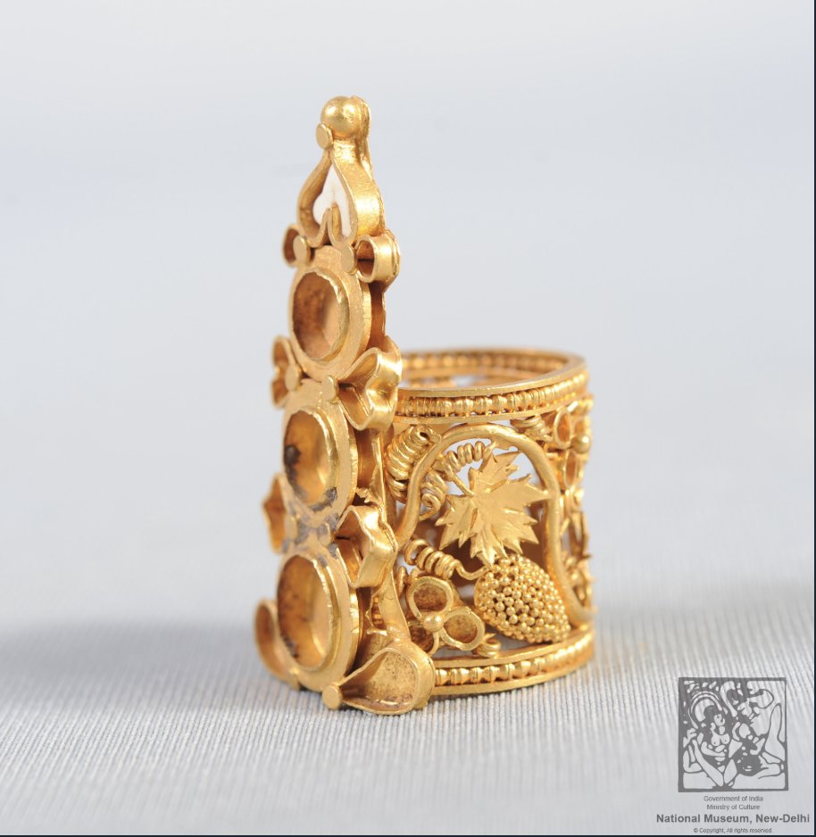 MumukshuSavitri's tweet photo. How did this woman get a history degree with such atrocious lack of knowledge? 

This gold finger ring from Sirkap, Taxila (c. 100 CE), from National Museum, New Delhi - already shows that Indian jewelers knew how to create fine filigree work made out of gold wires bent into S shaped scrolls, spiral coils and loops soldered onto the frame - at least a 1000 years before the 11th century. The elaborate hoop has a hallmark filigree scrolling design of acanthus leaves, vines, and bunches of grapes decorated with fine micro-granules within a beaded border, incorporating other advanced wire-working techniques like granulation (clusters of tiny fused gold spheres) and openwork. The three round hollows in front used to hold precious stones.

So Ruchika's ignorant claim that "that filigree work bracelet he is wearing, that tech comes up in the 11th c. in India" is patently false.