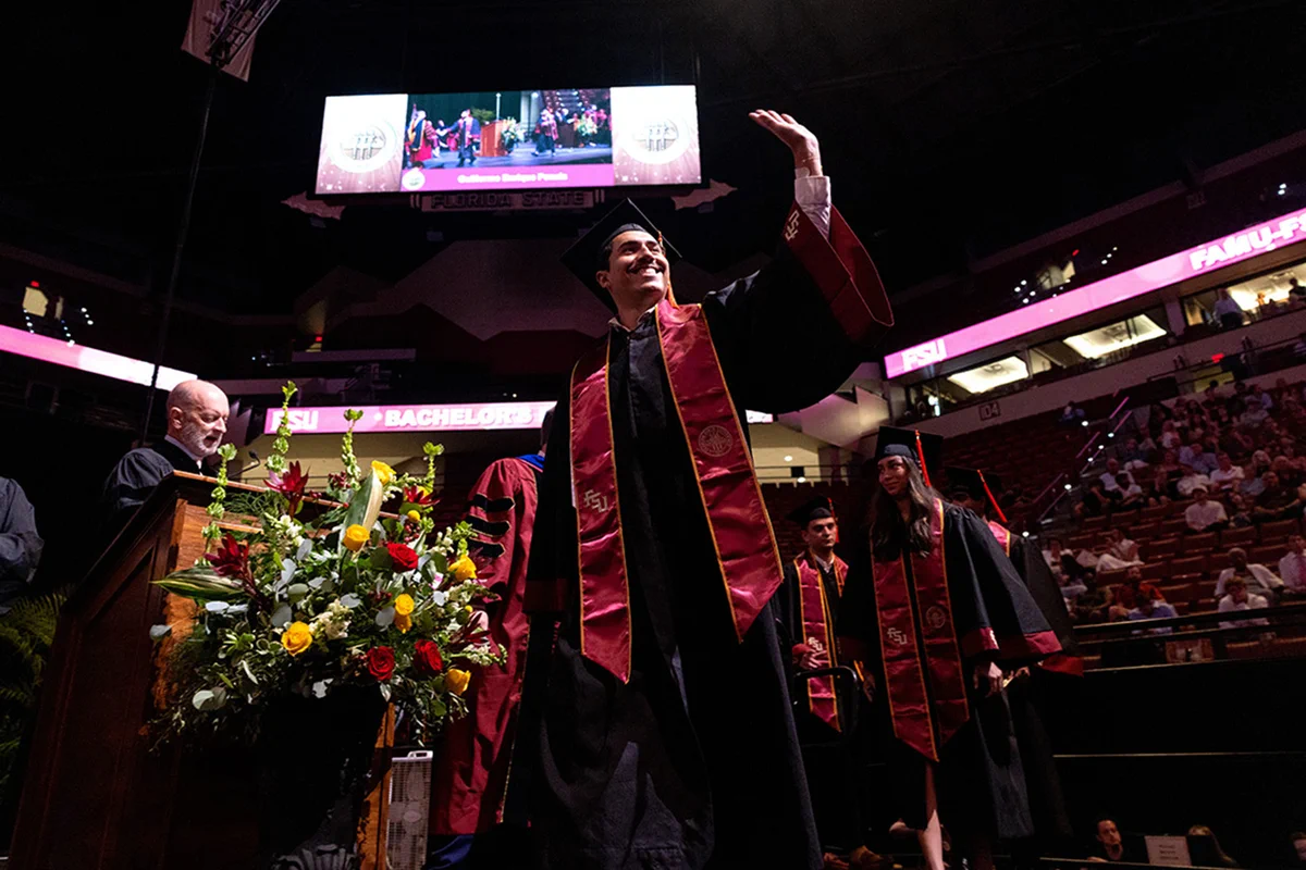 A graduate waves to the audience during Florida State University’s Summer 2026 commencement ceremony on Friday, July 31, 2026.