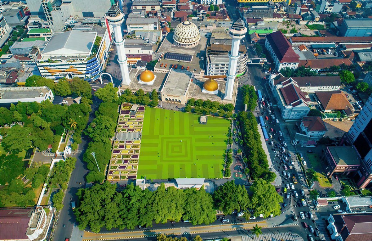 narachronicle's tweet photo. Banyak kota di Indonesia yang punya satu ruang publik dan bentuknya hampir selalu sama. Alun-alun, dan bentuknya hampir selalu persegi.

​Ini jelas bukan kebetulan belaka. Alun-alun tuh sebenarnya lahir dari cara pandang Jawa kuno soal pusat kekuasaan. Di depan keraton, biasanya dibuka sebuah lapangan luas berbentuk segi empat.

Bentuk itu sengaja dipilih karena ngasih kesan tertib, seimbang, dan gampang dikontrol. Dari sudut mana pun, ruang itu bisa diawasi dengan mudah. Dan dari sudut mana pun, orang bakal merasa lagi berdiri di tengah pusat kekuasaan.

​Di sebelah utara biasanya ada keraton atau pusat pemerintahan. Di selatan atau sekitarnya ada masjid. Lalu di sisi lainnya ada pasar atau ruang publik.

​Susunan kayak gini tuh bukan sekadar tata kota biasa. Ini adalah sebuah peta sosial. Siapa yang berkuasa di pusat, siapa yang ada di pinggiran, dan gimana caranya orang-orang harus bergerak di dalamnya.

​Pas kota-kota baru mulai tumbuh, pola ini terus ditiru. Bahkan di luar Pulau Jawa pun, banyak alun-alun yang tetep dibuat bentuk persegi karena model itu udah terlanjur dianggap sebagai standar ruang publik yang "resmi".

​Jadi yang sering kita liat sekarang bukan cuma sekadar lapangan kosong di tengah kota doang. Itu adalah sisa-sisa cara berpikir lama dalam mengatur dunia: bahwa pusat kekuasaan itu harus jelas, bentuknya harus teratur, dan ruangannya harus bisa dibaca sama siapa pun yang berdiri di dalamnya.

​Kadang tata kota yang kelihatannya paling biasa justru menyimpan cara berpikir yang paling tua.