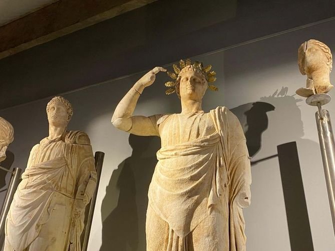Lucius_Gellius's tweet photo. Une statue en marbre de 2,7 mètres de haut représentant la déesse Hestia, découverte en 2 parties en 2005 lors de fouilles sur le site antique d'Aigai, dans l'ouest de la Turquie, est présentée au public un nouveau musée de Manisa ouvert en 2025 créé à cet effet. 

Elle est considérée comme la seule statue d'Hestia de la période hellénistique connue à avoir survécu jusqu'à nos jours. 

Hestia est la déesse protectrice vénérée des foyers et des villes dans la religion grecque antique . 

Chez les grecs, les statues d'Hestia étaient couramment placées dans les édifices du conseil (bouleuteria), symbolisant l'ordre civique et l'unité. 

Comme l'explique le professeur Yusuf Sezgin, directeur des fouilles d'Aigai et professeur d'archéologie à l'université Celal Bayar :

« Dans l’Antiquité, les décisions du conseil étaient prises en regardant Hestia droit dans les yeux. Elle incarnait l’unité, la stabilité et la boussole morale de la cité. »

La salle du musée qui accueille la statue reproduit l'agencement architectural de la salle du conseil originelle d'Aigai aux côtés d'autres statues honorifiques découvertes sur le site.

Située en Turquie occidentale, Aigai était l'une des douze cités antiques de la Ligue éolienne. Fondée dès le VIIIe siècle avant notre ère, la ville connut son apogée architectural et politique durant la période hellénistique.

Construite sur un terrain montagneux, Aigai présente des édifices publics exceptionnellement bien conservés, notamment un bouleutérion (maison du conseil) , une agora , un théâtre , des portiques,  des temples...