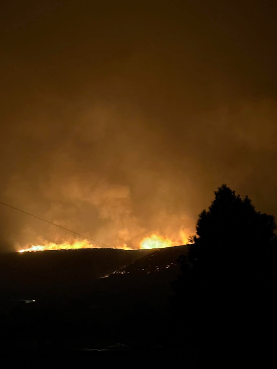 Bellingham_News's tweet photo. UPDATE: New photos show Sinlahekin Fire moving closer to Tonasket overnight

New images shared with Bellingham Metro News by Tuesday McAllister show the Sinlahekin Fire continuing to burn along the hillsides overlooking Tonasket as firefighters work through the night to slow its advance.

The latest photos capture long stretches of active fire, heavy smoke and glowing ridgelines just outside the community, highlighting how close the wildfire has come to populated areas. The fire’s glow can be seen from neighborhoods near the city as conditions remain dangerous.

Evacuation orders remain in effect for parts of the area, and officials continue urging residents to stay alert and follow all emergency instructions as the situation evolves.

Bellingham Metro News will continue providing updates as more information becomes available.

Photos courtesy of Tuesday McAllister, shared with permission.