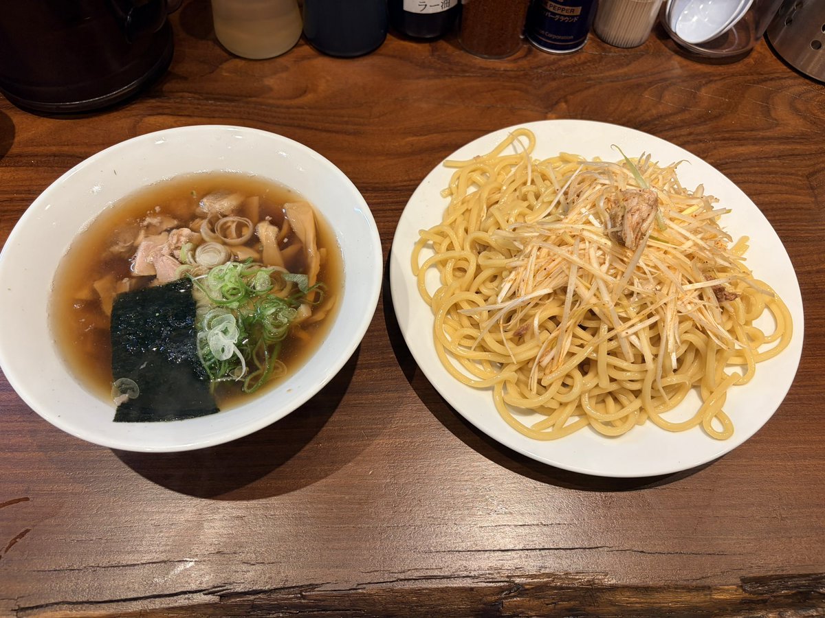 satodomingo's tweet photo. 「山梨うまうまラーメン探訪Vol.301」
「つけそば 七福」さんです‼️

昨日OPENしたばかり☺️
一福、さんぷくさんの系列店
＂つけそば一福直伝の味＂

当然行列に並びました🌼
そしたら鬼ゲリラ雷雨⛈️⛈️⛈️

雨宿りでお祝いの花に紛れながら
腹減らしながら
待った待ったよ約40分

注文するは、ネギつけそば大盛！
・・・・・・食した

美味い美味いよココの店‼️‼️
もちもち太麺を汁にダイブさせ
ネギは汁に浸けると辛味が流れるので

浸けた麺の上に辛ネギ乗せて食べてみて！
何とも言えない旨味の洪水
美味い美味いよココの店‼️‼️

大好きなメンマもたっぷり😍
サイコロチャーシューごろごろ🎲
相当な腹パン💦

〆はスープ割りしてゴックン
嗚呼、、、軽い感動すらある……

昇天‼️

#ラーメン