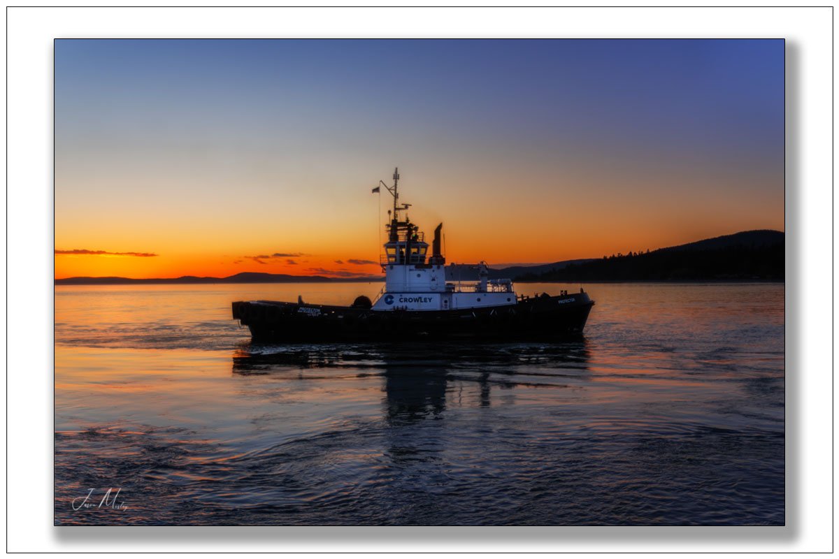 JasonMosleyPho1's tweet photo. Crowley's Tug Protector in Guemes Channel at sunset — orange fire on the horizon, glassy water, island silhouettes. https://t.co/yfI10G96Vc