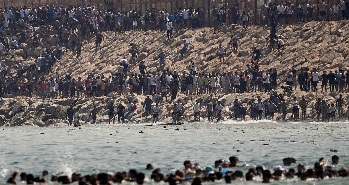 MohammedBenab11's tweet photo. Un grupo WhatsApp administrado desde Argelia identificado como principal actor en un Informe sobre la campaña de movilización digital vinculada a la reciente crisis migratoria en la ciudad de Ceuta. El informe ofrece un análisis de Inteligencia que consiste en reconstruir y evaluar esta campaña desarrollada entre el 15 de junio y el 2 de agosto de 2026. El documento examina la evolución del fenómeno desde una perspectiva cronológica, funcional y operativa, integrando la información obtenida mediante técnicas de Inteligencia de Fuentes Abiertas (OSINT), monitorización de redes sociales (SOCMINT) y análisis geoespacial (GEOINT), con el propósito de identificar los principales actores, plataformas, narrativas y mecanismos de propagación que
caracterizaron el proceso analizado.

El informe identifica un grupo
publico de WhatsApp denominado "سبتة كرياج هجمة" (Hijma Kiraj Sebta), la información analizada atribuye la administración del grupo a un número telefónico con prefijo internacional +213 (Argelia), que desempeñó funciones claramente operativas. Las evidencias documentadas indican la circulación de mensajes relacionados con la planificación del desplazamiento, la organización temporal de los movimientos y la distribución de instrucciones dirigidas a los participantes.
Entre las indicaciones documentadas durante la investigación figuran:
  constitución de pequeños grupos de acción;
  desplazamiento en horarios previamente acordados;
  reorganización de los participantes durante el desarrollo de la operación;
  preparación psicológica y fisica antes del intento de acceso;
  difusión de las convocatorias en el mayor número posible de páginas y perfiles sociales con el objetivo de ampliar su alcance;
  utilización como referencia de intentos anteriores de acceso realizados desde zonas boscosas próximas al perímetro fronterizo.
Desde una perspectiva de inteligencia, estas instrucciones presentan un nivel de elaboración superior al observado en publicaciones orientadas únicamente a la difusión de narrativas o a la amplificación de contenidos, circunstancia que otorga a este grupo una relevancia específica dentro del ecosistema digital analizado. @DiplomaciaM @DGSN_MAROC @FAR_MAROC @HorizonsInstit @Atalayar_ @le360es @Mares30com @elconfidencial