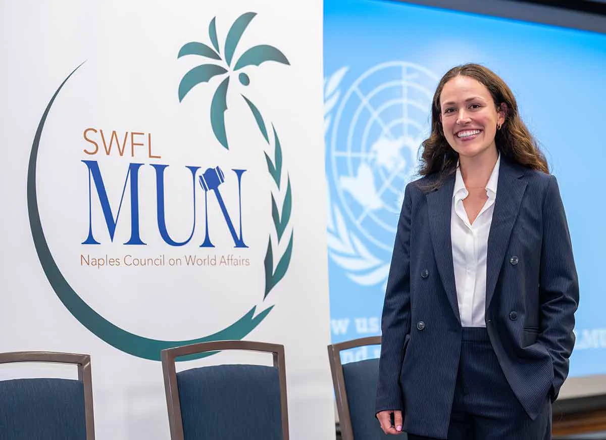 a photo of a student in front of a banner that reads SWFL MUN Naples Council on World Affairs