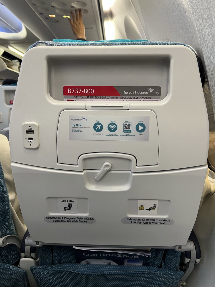 Catatantanpatgl's tweet photo. Pagi ini aku terbang ke Palu pakai Garuda Indonesia. Begitu masuk kabin, langsung terasa suasananya rapi dan tampilannya masih kinclong seperti pesawat baru. Setelah cari tahu, ternyata memang armada tersebut baru bergabung dan sebelumnya dioperasikan oleh Malaysia Airlines.

Ada satu perubahan yang cukup bikin kaget. Layar hiburan yang biasanya menempel di kursi penumpang sudah tidak ada lagi. Sebagai gantinya, seluruh sistem hiburan dipindahkan ke platform digital yang bisa diakses lewat koneksi Wi-Fi menggunakan perangkat masing-masing.

Rasanya pengalaman terbang dengan Garuda sekarang sedikit berbeda. Lagu penyambutan bernuansa budaya daerah yang dulu sering diputar juga sudah tidak terdengar, sehingga atmosfer kabin terasa lebih biasa. Selain itu, sandaran kepala di kursi juga sudah tidak dipasang lagi. Akibatnya, kalau penumpang di sebelah tertidur sambil miring, kepalanya jadi lebih mudah bersandar ke arah kita. 😅