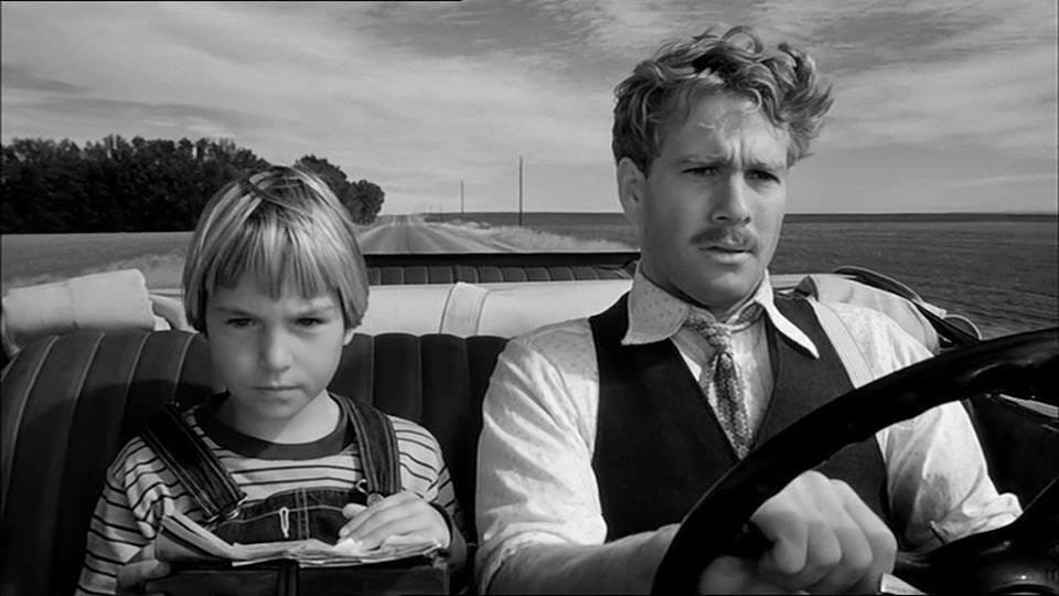 ArFiMoFlCr's tweet photo. My Favorite Films

Paper Moon (1973)

Director Peter Bogdanovich's (The Last Picture Show) 1973 depression era comedy adpated from Joe David Brown's novel "Addie Pray" is most known for Tatum O'Neal winning an Oscar at age 10. Daughter of Ryan O'Neal (who also stars along with her), Tatum's career never really went anywhere after this and became more famous for being married to tennis star John McEnroe and her strained relationship with her farher.
But none of that should take away from this marvelous movie. Filmed in crisp black and white, Paper Moon is about con man Moze Pray, who makes his living by conducting a bible ordering scam on recently widowed women, who arrives at the funeral of one of his lovers. Her orphaned daughter Addie, with no family nearby willing to take her in, is there and many of the people at the funeral suspect Moze to be her father. When he agrees to drive Addie to some relatives in Missouri, he cons the brother of the man who caused the accident that killed Addie's mom, but Addie overhears and when they go to a diner for some food, the little quiet girl shows her resolve and demands that Moze pay her back the money that was rightfully hers. Thus begins their adventure, as the go across the midwest, teaming up to con their way to Missouri as they begin to develp a close bond, through thick or thin. Or in this film, Madaline Kahn one of the funniest woman to have existed. Known for her roles in the Mel Brooks' films "Young Frankenstein" and "Blazing Saddles" (where she earned back to back best supporting actress oscar nominations with this after "Paper Moon"), Kahn has a short but unforgettable performance as Trixie Delight, a woman that Moze meets and, much to Addie's disdain (as she now has to fight for Moze's attention), brings along for their road trip. Trixie's young attendant. Imogene (played by a talented P.J. Johnson, who only made one more film and basically vanished) is also irritated with the situation and makes a good ally with Addie. Randy Quaid has a very small role (just like in The Last Picture Show) as well as John Hillerman (Magnum, P.I.).
It's really refreshing to watch a comedy with such beautiful cinematography that really makes you feel stranded in the middle of the great plains. Its funny, surprisingly touching (I still cry during the last shot), and while I won't argue the validity of Tatum's Oscar win, she had the gift of deadpan comedy and is really the main actress of the film. Give it a shot and tell me what YOU think.

Rating: 🌟🌟🌟🌟🌟 Movie (I had a hard time with this one and I could change it to Film. Thoughts?)