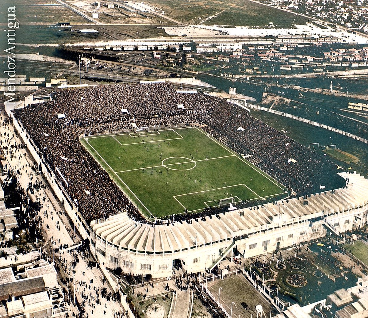 MendozAntigua's tweet photo. 1935: EL TEMPLO ROJO ANTES DE SER “DOBLE” — LA VISTA AÉREA QUE CONGELÓ PARA SIEMPRE LA PASIÓN DE AVELLANEDA

https://t.co/zGqC7xehxu

Esta extraordinaria vista aérea, atribuida a 1935, nos transporta al corazón de una Avellaneda obrera, ferroviaria y profundamente futbolera. Allí aparece el estadio de Independiente levantado en la histórica esquina de Alsina y Almirante Cordero —actual calle Ricardo Enrique Bochini—, exactamente en el mismo lugar donde hoy se encuentra el estadio Libertadores de América–Ricardo Enrique Bochini. Existe, sin embargo, una importante precisión histórica: la fotografía no fue tomada antes de la construcción del estadio, porque la cancha ya había sido inaugurada el 4 de marzo de 1928 con un multitudinario amistoso ante Peñarol de Montevideo que terminó 2 a 2. Lo que la imagen muestra es al escenario rojo antes de recibir la segunda visera, obra que recién se estrenaría el 20 de agosto de 1961 y que daría origen al nombre popular de “Doble Visera”. Para construir aquel coloso, Independiente aceptó un desafío que muchos consideraban imposible: transformar el inundable “Pantano de Ohaco” en uno de los estadios más modernos del continente. El terreno fue rellenado con enormes cantidades de tierra y allí se levantó el proyecto del ingeniero Federico Garófalo, cuya tribuna principal contaba con una innovadora visera de cemento armado en voladizo, sin columnas que interrumpieran la visión. Fue reconocido como el primer gran estadio de cemento de Sudamérica. Además, en 1930 el campo de juego había sido girado noventa grados y adoptado una orientación norte-sur. Por eso, esta fotografía de 1935 retrata una etapa única: el estadio ya había cambiado su disposición, sus tribunas aparecían desbordadas por una multitud, pero todavía poseía una sola visera. No era aún la célebre Doble Visera, aunque ya comenzaba a convertirse en uno de los grandes templos del fútbol argentino. Entre vías ferroviarias, chimeneas, talleres y tribunas repletas, Independiente empezaba a levantar mucho más que una cancha: construía el escenario donde décadas después nacerían hazañas, ídolos y noches inolvidables que transformarían al Rojo en el Rey de Copas. #Independiente #ClubAtleticoIndependiente #DobleVisera #ReyDeCopas #Avellaneda #FutbolArgentino #HistoriaDelFutbol #EstadiosHistoricos #FotografiaHistorica #ArchivoHistorico #MemoriaFutbolera #PasiónRoja #FootballHistory #ArgentineFootball #HistoricStadium #VintageFootball #FootballMemories #IndependienteFC #AvellanedaHistory #KingOfCups