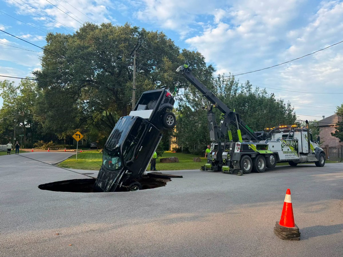 KHOU's tweet photo. A massive hole opened up in a Beaumont road early this morning, swallowing a pickup truck.  What we know: https://t.co/aq0zUSnwhA https://t.co/1sImhmdqpo