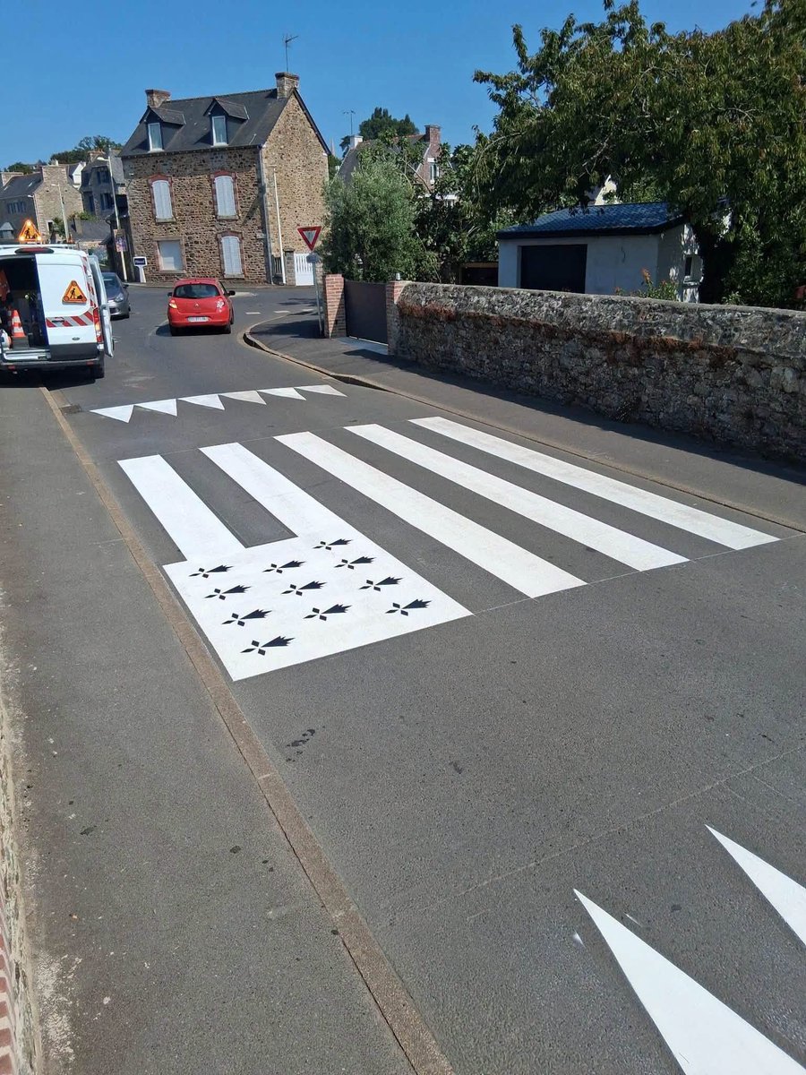 Mammbreizh's tweet photo. À Pléneuf-Val-André, dans les Côtes-d’Armor, les agents municipaux ont repeint fin juillet un passage piéton de la rue Clemenceau. Bandes blanches allongées, hermines noires :
vu d’un peu plus loin, c’est un immense Gwenn ha Du, le drapeau breton, qui apparaît sur la chaussée 😍 https://t.co/VB00ml56cv