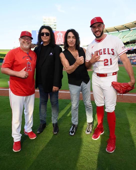 Angels Staff Assistant Tim Buss, KISS members Gene Simmons and Paul Stanley, and Grayson Rodriguez pose for a photo on the field together following the ceremonial first pitch at Angel Stadium. 