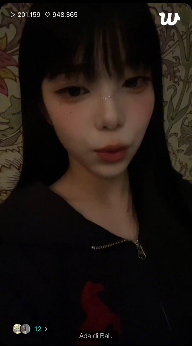 A selfie video shows a woman with long black hair, bangs, and a nose piercing, wearing a black zip-up hoodie with a red design, captioned "Ada di Bali" with 201.159 views and 948.365 likes. The "Happy ian" caption suggests she is sharing a cheerful update about being in Bali.
