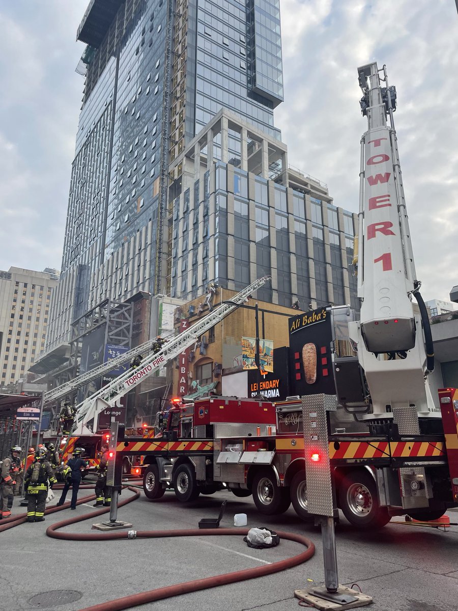 Toronto_Fire's tweet photo. TFS on scene of a 3-Alarm fire on Yonge Street, downtown at Elm Street. Crews responded for a fire on the roof and arrived to heavy black smoke. Crews are actively fighting fire with areas of the structure now deemed compromised.  No reported injuries. #toronto ^dc https://t.co/4oiDtrIaB7