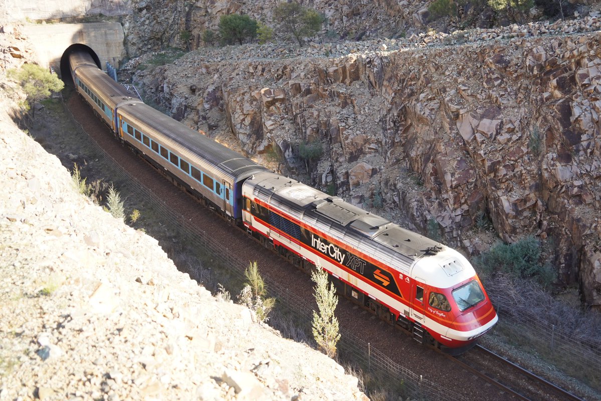 AunzRailfan's tweet photo. メルボルンXPT最大の見所とも言えるループ線、Bethungra Spiralを前日とは逆の位置から撮影。どんなループ線かわかるよう撮影画像��ChatGPTで即席合成。
今回のXPTはメルボルン側機関車のみキャンディ復刻塗装。トンネルを通り、山を一周して上り線路が交差する様をより一層目立たせてくれました。 https://t.co/GC4XiYFZ2s
