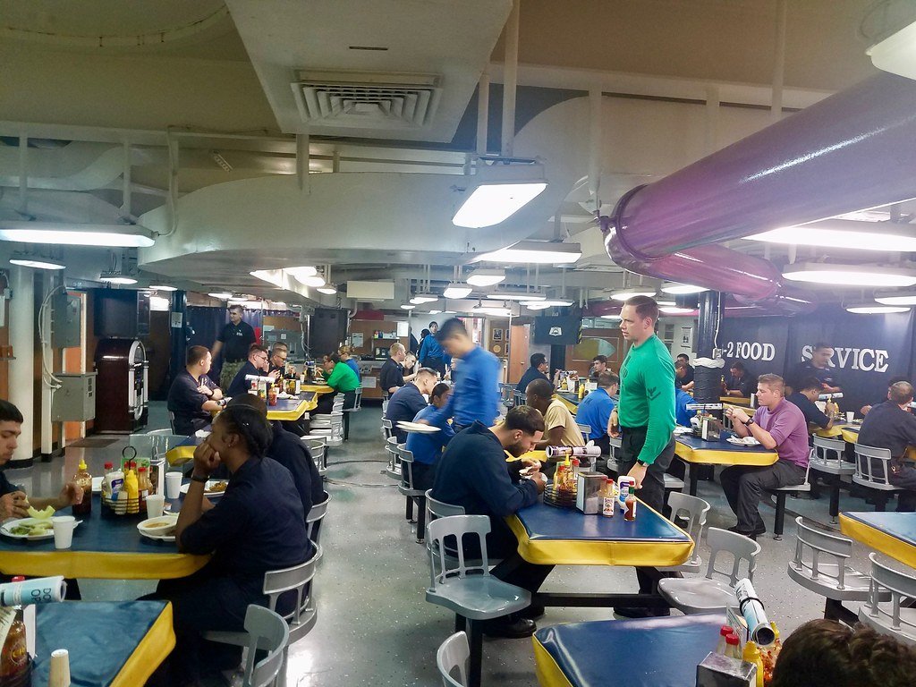 FreedomDude71's tweet photo. Ignore the fake posts claiming to show what the mess decks on aircraft carriers look like.

These ships have two crew mess decks—forward and aft on the second deck. There are also wardrooms for officers and a separate mess for E-7 and above (Chiefs). None of them feature cinder-block construction. For those of you in the back: ships are built of steel.

Food service on a ship the size of an aircraft carrier is a monumental operation that runs 24/7 when the ship is at sea. Even when flight ops aren’t happening, the galleys keep going.

I’m former Navy and spent a lot of my time on carriers. In all those years, I can honestly say I never had a meal like the ones the fake news is claiming were served. Sure, some meals were better than others, and the food could get monotonous after a long stretch at sea. But I ate well in the Navy. You could get something to eat nearly 24 hours a day, not to mention the snacks and sodas from the geedunk machines.

These images are exactly what mess decks look like. If you’re even remotely buying the fake news reports about the USS Lincoln, you need to check yourself and question your own judgment.

Get the facts—stupid is a choice.
