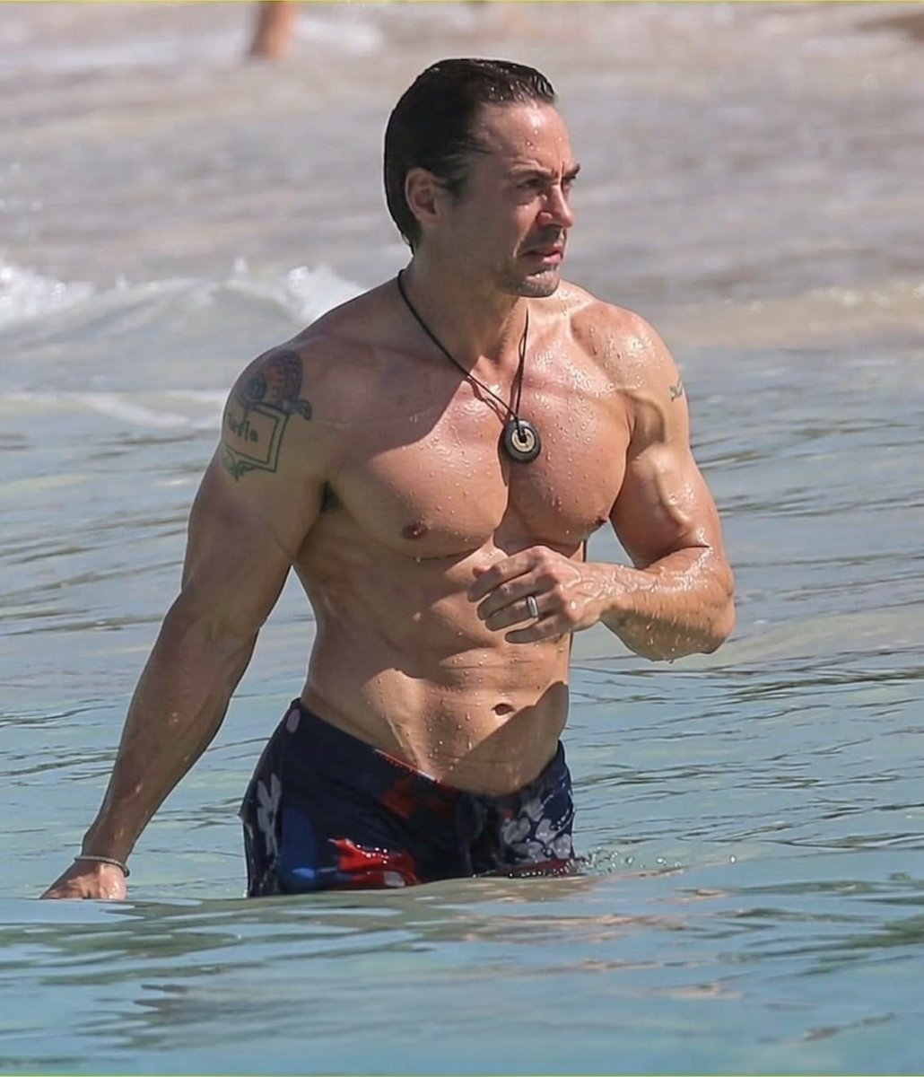 PridePopCulture's tweet photo. Robert Downey Jr shirtless at the beach showing defined chest and arms https://t.co/g3TPDtMkXu