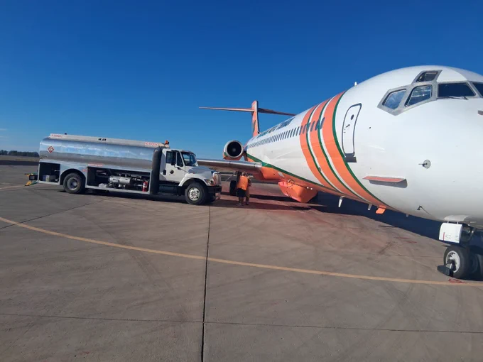 Fuel truck refueling a large airtanker on a clear day on the tarmac. 