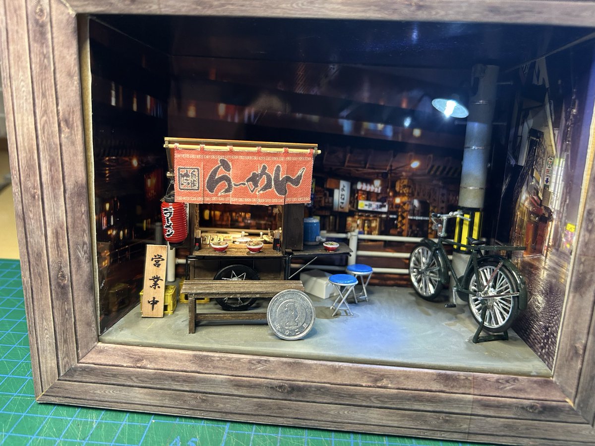 TOY_STEP1's tweet photo. 本日、完成した　久しぶりに屋台を作った　スケールは1/25 LEDも取り付けて　それなりの雰囲気ができた　ガチャガチャであった　ネコ店主も置いてみた https://t.co/Fzqd5g9uCv