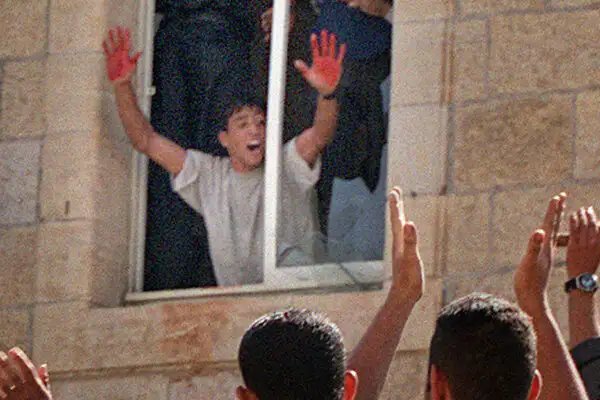 Sarahsa09309757's tweet photo. En 2000, deux Israéliens sont entrés par erreur à Ramallah.

 Ils ont été conduits dans un poste de police de l'Autorité palestinienne, où une foule les a lynchés à mort. 

Des images montrent un homme exhibant ses mains couvertes de sang à la fenêtre, tandis que la foule en contrebas applaudit et exulte. 

Il n'y avait qu'une seule célébration : le sang et la mort. N'oubliez jamais.