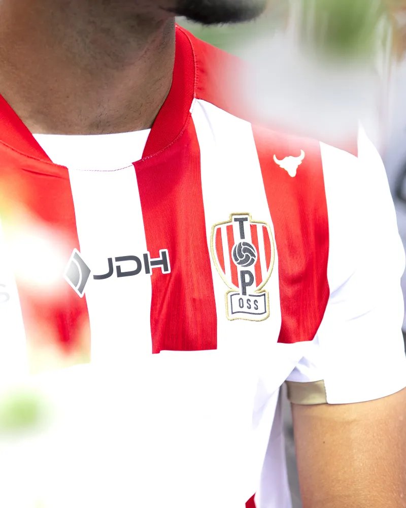 oranjefussball's tweet photo. Ein Tag vor dem Saisonstart präsentieren #TOPOss und #JDH das Heimtrikot 2026/27: Das Vereinslogo ist echt aufgestickt, was dem Design eine kraftvollere Wirkung verleiht. Zudem glänzt das „Lucky Charm Oss“-Logo auf dem Outfit &amp; der Nackenspruch unterstreicht den Kampfgeist. https://t.co/W4qEf7lqGJ