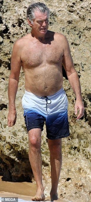 Emmy_jay231's tweet photo. Pierce Brosnan, 64, perfects his posture with some driftwood as he goes shirtless on the beach in Hawaii. https://t.co/NESZh3Oeen