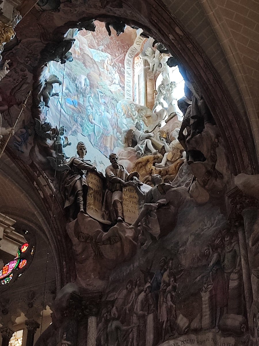 trastamara_ana's tweet photo. Narciso Tomé creó, ayudado por sus cuatro hijos (que vivían en una casa en la Plaza de San Justo, a pocos pasos de la Catedral), la más monumental y maravillosa obra de arte que encontramos en la Catedral Primada de España.

La genialidad de Narciso Tomé consistió en abrir un óculo (un gran hueco o lucernario) en la propia bóveda gótica de la girola. De este modo, la luz natural del sol penetra desde el exterior a través de la cubierta de la catedral, atraviesa la estructura esculpida y traspasa ("hace transparente") el retomo para iluminar directamente y de forma cenital el Sagrario. Para los fieles, esta irrupción de luz solar era una clara metáfora visual de que Dios es la luz y de la glorificación de la Eucaristía.

En la base del conjunto, Tomé dejó una inscripción firmando su obra con orgullo —algo poco habitual en la época—, proclamando que él mismo se había encargado de delinearla, esculpirla y pintarla.

Es probable que, anteriormente, existiera algún tipo de transparente medieval en esta misma ubicación, y que fuera sustituido por la obra de Tomé. También, según la documentación de la obra y fábrica de la Catedral, aquí hubo una serie decorativa en pintura sobre la Coronación de la Virgen realizada probablemente por Giotto, desaparecida al edificar el actual Transparente (aquí se ubicaría una puerta de acceso a la antigua capilla de la Santa Cruz, que fue sustituida por la Capilla Mayor).

En su época, la obra generó opiniones divididas. Los sectores más puristas o defensores del clasicismo criticaron su desbordante barroquismo, considerándolo un exceso (horror vacui) que rompía con la armonía medieval del templo gótico. Sin embargo, con los siglos se ha consagrado universalmente como una de las obras cumbre del arte barroco europeo.

#ArteBarroco
#Toledo